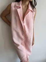 Vestido camisero corto color rosa, sin mangas, con cuello clásico y cierre frontal con botones.