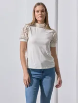 Blusa color blanco de crepe, marca Cable & Gauge. Cuello halter con detalles plisados y mangas cortas de encaje con destellos brillantes.