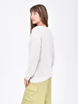 Buzo de tejido de punto color beige claro, con escote en V y manga larga.