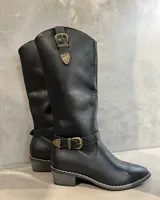 Botas texanas negras de caña alta, con detalles de hebillas decorativas en dorado envejecido en la parte superior y alrededor del tobillo. Tienen punta afilada y tacón bajo.
