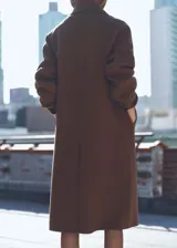 Abrigo marrón de lana con doble botonadura, cuello con solapa de muesca, dos bolsillos laterales, hombros caídos, diseño oversize y largo, con forro interior.
