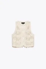 Chaleco abierto de punto color crudo con manga sisa y detalle de conchas en el ruedo.