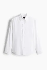 Camisa blanca de lino y algodón con cuello inglés, tapeta clásica y canesú en la espalda. Modelo de manga larga con bolsillo superior abierto, cierre ajustable de botón en los puños y tapeta con botón. Bajo redondeado. Corte estándar.