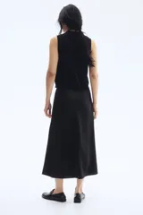 Pollera midi negra con leve brillo y caída suave. Modelo de tiro alto con elástico oculto en la cintura y leve vuelo en el bajo.