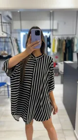 Camisa oversize con estampado de rayas verticales blancas y negras, cuello mao y cierre frontal con botones.