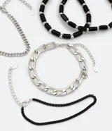 Set de cinco pulseras para hombre, con dos pulseras de cadena plateada de diferentes grosores, una pulsera de cuentas negras con detalles plateados, una pulsera de cuentas negras facetadas y una pulsera de cadena negra.