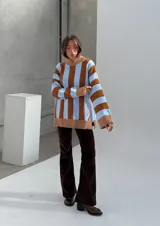 Sweater de punto con cuello alto negro y rayas verticales marrones y blancas.