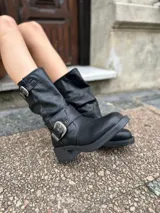 Bota corta negra de cuero con hebillas plateadas y taco bajo.
