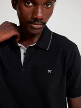 Camisa polo color rosa claro con cuello clásico, tapeta de dos botones y bordado de logo en el pecho. Presenta ribete azul marino en cuello y mangas. Corte clásico.