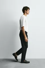 Jeans de denim de algodón, color negro lavado, con tiro medio, corte ajustado en cadera y muslos, y pierna que se estrecha hacia el tobillo. Presenta cinco bolsillos y cierre frontal con cremallera y botón.