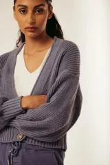 Cárdigan de punto grueso color gris con mangas largas abullonadas y cierre frontal con un botón.