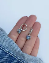 Aritos colgantes plateados con forma de corazón y strass azules.