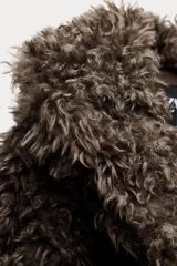 Abrigo corto de pelo sintético color marrón, con cuello solapa y manga larga. Tiene bolsillos delanteros, forro interior y cierre frontal con ganchos metálicos forrados.