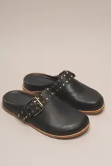 Sueco destalonado de cuero vacuno color negro, con hebilla ajustable dorada y detalles de tachas doradas.