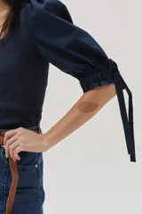 Top azul de tejido de punto con cuello cuadrado y mangas abullonadas con lazos.