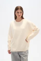 Sweater color crema, de corte holgado, con cuello redondo y mostacillas decorativas.
