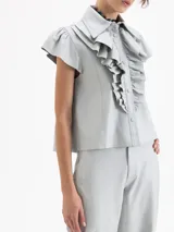 Camisa de cuero ovino negra, con volados en el centro delantero, mangas con volumen fruncidas en la copa y broches forrados en cuero.