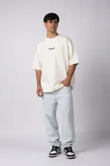 Remera color crema de corte oversize con la palabra "Rewind" bordada en el frente.