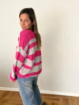 Sweater tejido a rayas fucsia y gris, con cuello en V, calce relajado y mangas amplias estilo balloon.