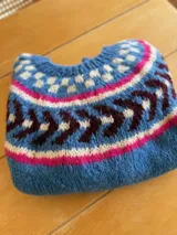 Sweater tejido a mano en lana mohair premium, color celeste con diseño geométrico en blanco, rosa y marrón.