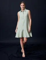 Vestido corto blanco de gasa, sin mangas, con cuello camisero, abertura central con botones y terminación de ruedo con volado.