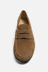 Mocasín color marrón de cuero con acabado serraje, antifaz, horma redonda y suela con ligero tacón.