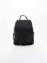 Mochila negra con textura granulada, solapa frontal y cierre de cordón ajustable. Cuenta con bolsillos laterales, asa superior y un detalle de dije plateado en el cierre lateral.