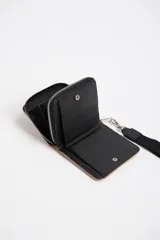 Billetera de diseño capitoneado de color beige, con cierre y asa para llevar.