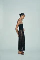 Vestido midi semitransparente de encaje negro, con escote recto, tirantes finos ajustables, forro interior tipo body con aros y abertura lateral en el bajo.