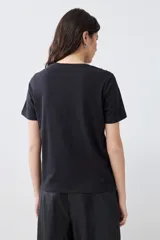 Remera negra de manga corta con apliques bordados en el escote.