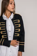 Chaqueta corta negra de paño con corte entallado, detalles dorados bordados, botones metálicos y cuello redondo.