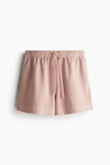 Short rosado de felpa de algodón, con cintura elástica ajustable con cordón, bolsillos laterales y traseros, y aberturas laterales en el ruedo.