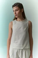 Top sin mangas de lino metalizado color beige, con cuello redondo y detalle trenzado en el borde.