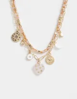 Collar corto dorado de doble cadena, una de eslabones y otra de cuentas facetadas color durazno. Incluye dijes colgantes de estrella, luna, corazón, ojo turco y medallones.