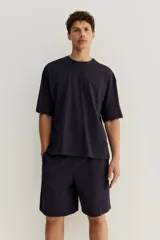 Conjunto de pijama corto de dos piezas. Remera negra de punto de algodón liviano con cuello redondo ribeteado acanalado, hombros caídos y bajo recto. Short negro en popelina de algodón con elástico revestido en la cintura, cierre de botón, bolsillos laterales y un bolsillo parche atrás.