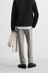 Pantalón slim fit negro confeccionado en tejido con elasticidad en ambas direcciones. Cuenta con bolsillos frontales y traseros de vivo con botón. Cierre frontal con cremallera y botón.