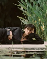 Collar con dije dorado irregular con agujero central, colgando de cordón negro ajustable.