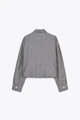 Camisa corta gris con rayas verticales blancas, cuello solapa y manga larga. Cierre frontal con botones.