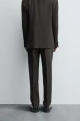 Pantalón de vestir negro de lana, corte recto, con bolsillos laterales y traseros de ojal con botón.