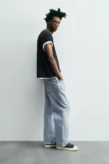 Pantalón de jean gris oscuro, corte amplio, con cinco bolsillos, efecto lavado y cierre frontal con cremallera y botón.
