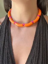 Collar corto tipo choker compuesto por cuentas cilíndricas acrílicas de color naranja brillante intercaladas con cuentas esféricas pequeñas de color fucsia.