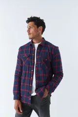 Sobrecamisa de algodón para hombre con interior de corderito, estampado a cuadros en tonos negro, blanco y azul. Tiene cierre de botones, bolsillos tipo cartera y logo en goma. El modelo usa talle M.