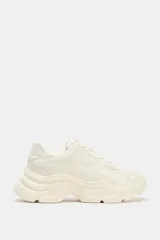 Zapatillas deportivas color crema con suela chunky, capellada combinada en cuero sintético y tejido texturizado, cierre con cordones y plataforma de 5 cm.