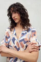 Camisa de manga corta con estampado de hojas blancas sobre fondo celeste, cuello solapa y botones de nácar al frente. Confeccionada en tejido liviano de sutil textura.