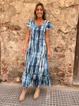 Vestido largo con estampado tie-dye en tonos azules y blancos, con mangas cortas con volados y falda con volados en el ruedo.