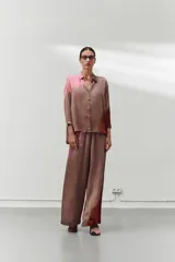 Pantalón largo de pierna ancha color marrón con estampado degradado en tonos rosados y rojizos. Tiene cintura elástica, bolsillos laterales y costuras delanteras y traseras.