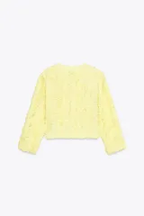Chaqueta corta color amarillo pastel con textura de volantes, cuello redondo, manga larga y cierre frontal con botón a presión oculto.