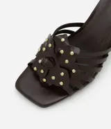 Sandalia mule color marrón con punta cuadrada, tira con flor y aplicación de strass, y tacón fino alto.