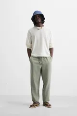 Pantalón color arena de corte recto, confeccionado en tejido de algodón y lino. Cuenta con cintura elástica ajustable con cordón, bolsillos delanteros y traseros de parche.