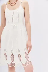 Vestido blanco corto de algodón con breteles finos y detalle de puntilla en el ruedo.